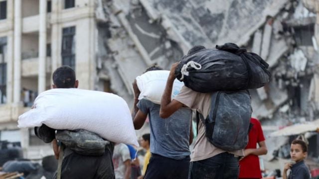 Palestinians carry aid supplies after trucks loaded with aid entered from Israel through central Gaza, in Gaza City on 22 July 2025.
