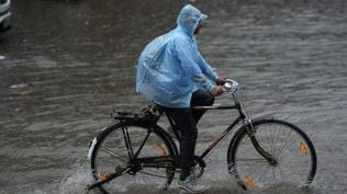 A man makes his way through a waterlogged road amid rainfall, in New Delhi