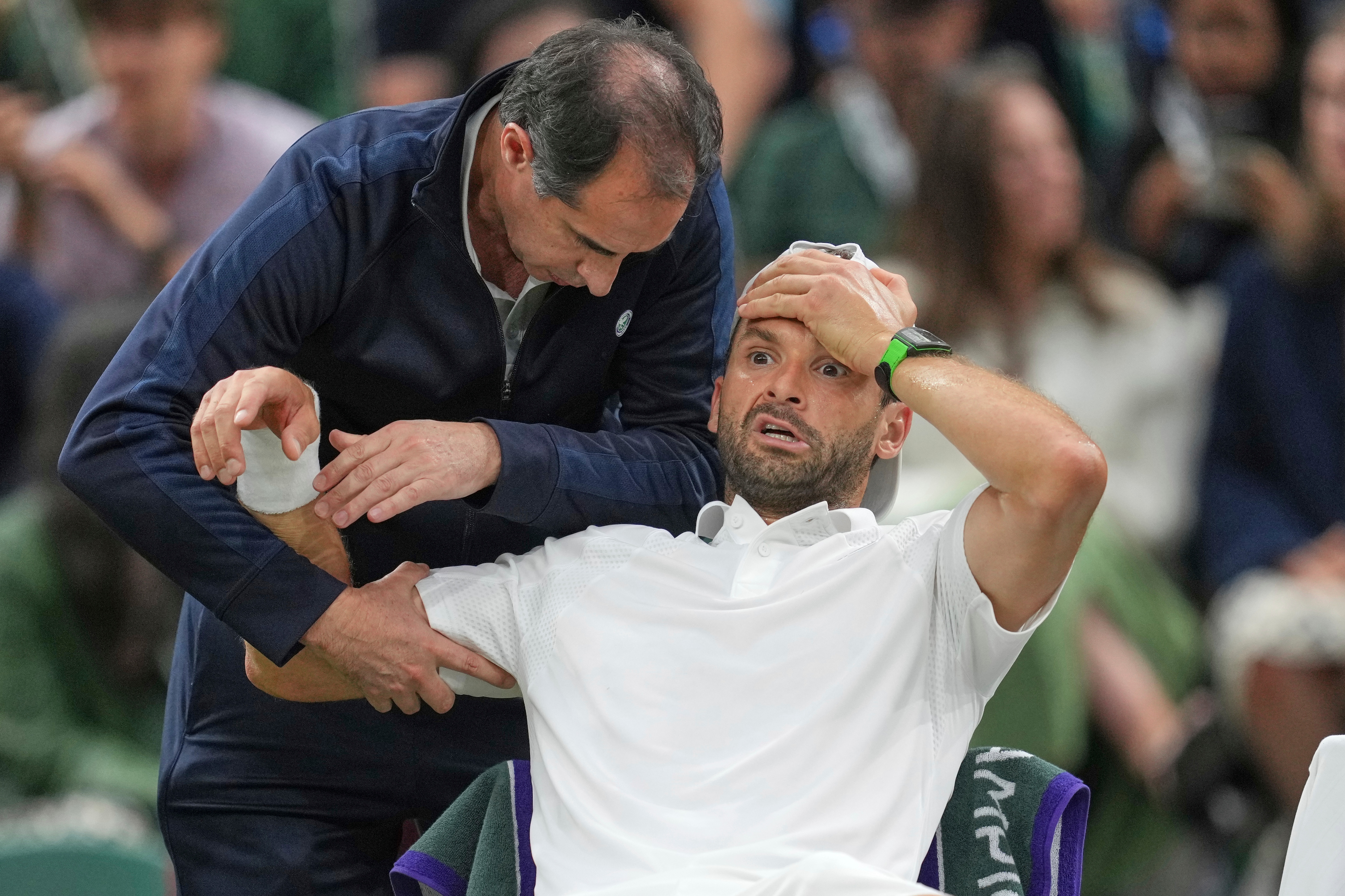 Bulgaria's Grigor Dimitrov gets treatment after he went down with an injury which forced him to retire injured from a fourth round men's singles match against Italy's Jannik Sinner at the Wimbledon Tennis Championships in London, Monday, July 7, 2025. (AP Photo/Kin Cheung)