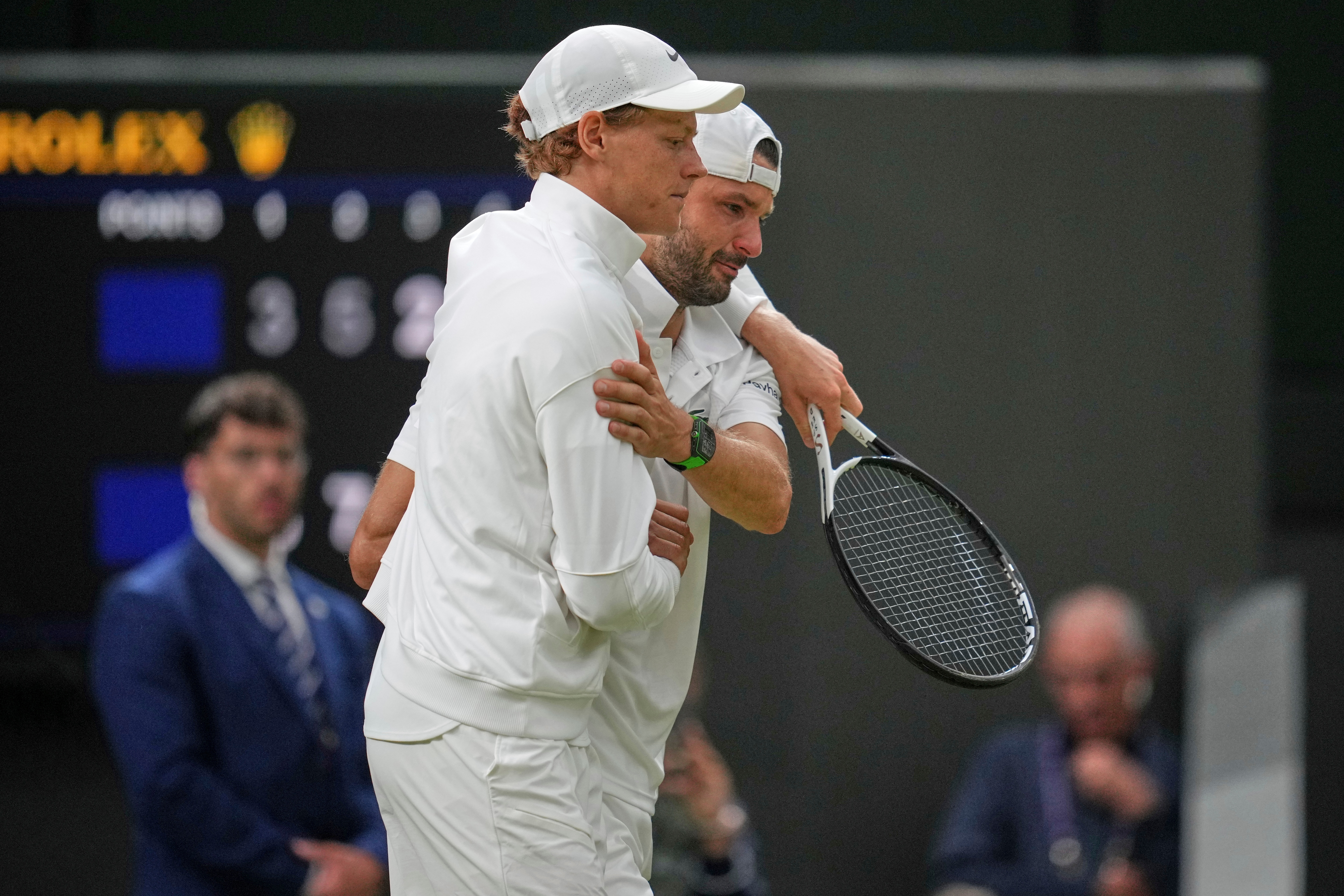 Italy's Jannik Sinner, left, assists Bulgaria's Grigor Dimitrov after he went down with an injury which forced him to retire from a fourth round men's singles match at the Wimbledon Tennis Championships in London, Monday, July 7, 2025. (AP Photo/Kin Cheung)
