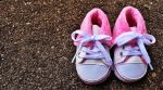 shoes of a small child of blue nad pink colour on a surface made up of gravel ivf