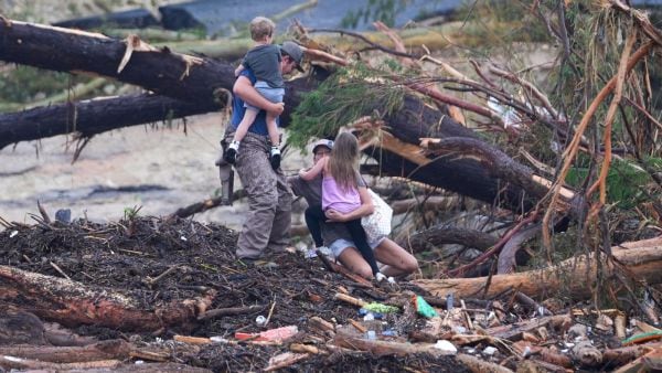 A woman falls while climbing with others over debris on a bridge atop the Guadalupe River after a flash flood swept through the area