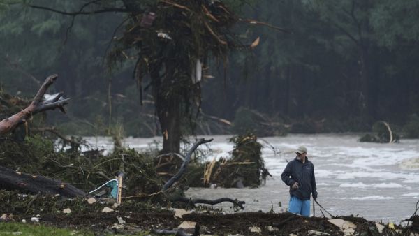 A man surveys debris along the Guadalupe River after a flash flood struck the area
