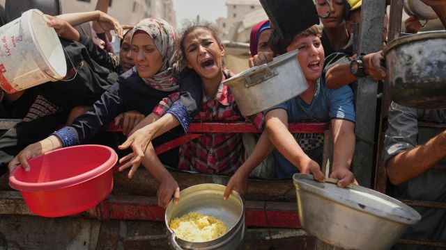 Palestinians struggle to get donated food at a community kitchen in Gaza City, northern Gaza Strip, Saturday, Aug. 16, 2025. (AP Photo/Jehad Alshrafi, File)