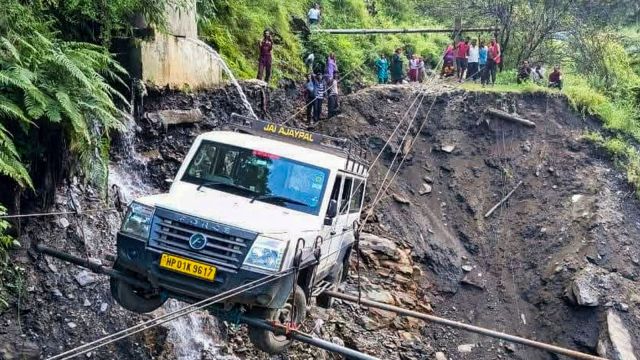 A vehicle being lifted from the debris of a damaged road after heavy rainfall, in Kullu district, Himachal Pradesh