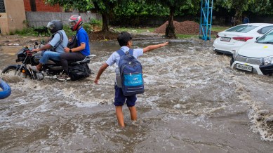 A student wades through a waterlogged road after heavy rainfall.