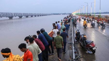 People look at the swollen River Ganga from a bridge during the monsoon season