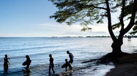 FILE -People wade into the waters of Lake Victoria, the world's second-largest freshwater lake, Nov. 25, 2024, in Entebbe, Uganda. (AP Photo/David Goldman, File)