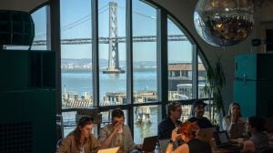 People work at a space called Shack15 inside the Ferry Building in San Francisco, with a view of the San Francisco–Oakland Bay Bridge, on May 8, 2025. Artificial intelligence has ushered in an era of what insiders in the nation’s innovation capital call “hard tech.” (Loren Elliott/The New York Times)