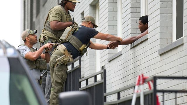 Armed Officers place handcuffs on a man from within an apartment complex, Tuesday, Aug. 19, 2025, in the Petworth neighborhood of northwest Washington. The officers pictured had "Washington Field Office" on their shirts underneath tactical gear that said Police. (AP Photo/Jacquelyn Martin)