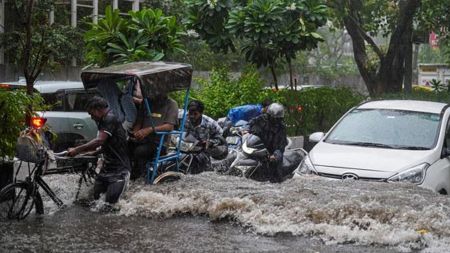 Commuters wade through a waterlogged road amid heavy rainfall, in New Delhi
