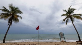 A red flag warns of dangerous waves on an empty beach in San Juan, Puerto Rico, after Hurricane Erin passed by near the island