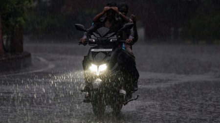People ride a scooter amid heavy monsoon rain
