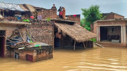 People on the roof of partially submerged houses as the water level of the Yamuna river increases following rainfall, in Kanpur,
