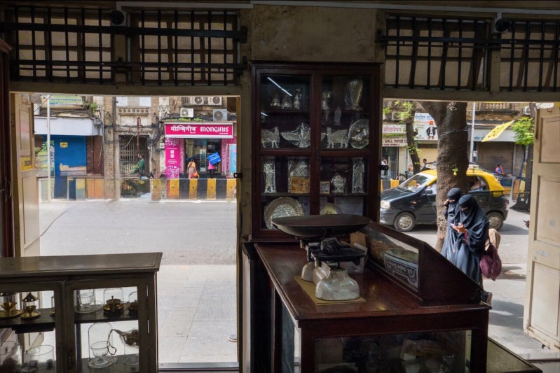 A shop selling Zoroastrian icons with two burka clad women and a nimbu mirchi talisman outside – an image emblematic of the vibrant diversity of Bombay (Rahul Patel)