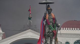 A protester celebrates standing at the top of the Singha Durbar, the seat of Nepal's government's various ministries and offices, after it was set on fire during a protest against social media ban and corruption in Kathmandu, Nepal, Tuesday, Sept. 9, 2025. (AP Photo/Niranjan Shrestha)