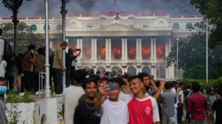 Protesters take selfies and celebrate at the Singha Durbar, the seat of Nepal's government's various ministries and offices, after it was set on fire during a protest against social media ban and corruption in Kathmandu, Nepal, Tuesday, Sept. 9, 2025. (AP Photo/Niranjan Shrestha)