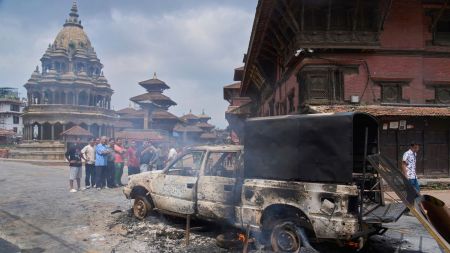 People look at a burnt police vehicle during protests against social media ban and corruption in Kathmandu, Nepal