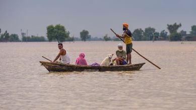 Locals along with a dog ride a boat to move through a flooded area, in Kapurthala, Punjab, Wednesday, Sept. 3, 2025.