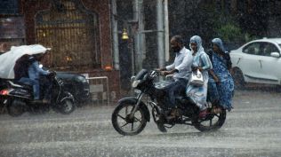 Commuters make their way amid heavy rain, in Kanpur on Tuesday.
