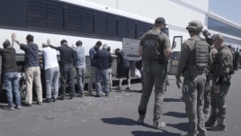An image from a video provided by US Customs Enforcement showing employees waiting to have their legs shackled at a Hyundai manufacturing plant in Georgia