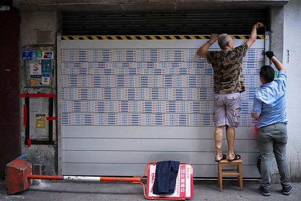 residents install flood barriers at a doorway of a building ahead of approaching Super Typhoon Ragasa, in Macao