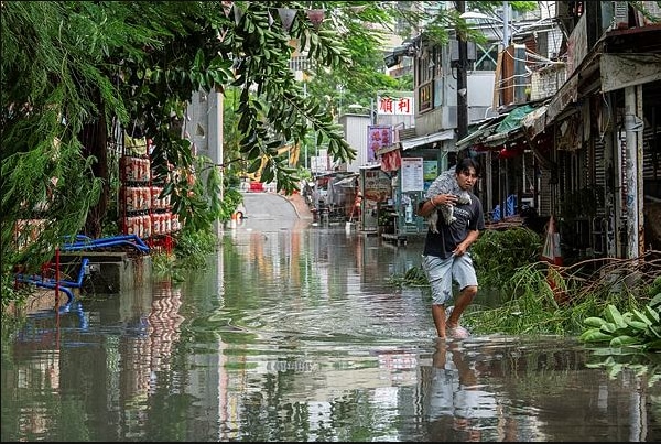 A resident carries a pet as he walks through the floodwaters in Lei Yue Mun area, Hong Kong