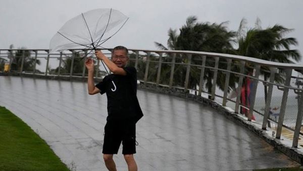 A man holds on to his umbrella against strong winds ahead of Super Typhoon Ragasa in Shenzhen in southern China's Guangdong province