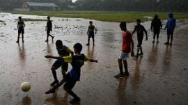 A group of boys plays football amidst rain, at Shivaji Park in Mumbai.