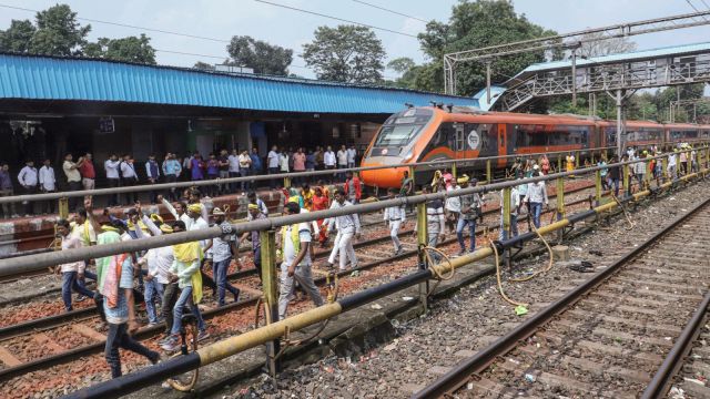 Protestors under the banner of 'Adivasi Kurmi Samaj' walk on railway tracks during a rail blockade, demanding Scheduled Tribe status, at Muri railway station