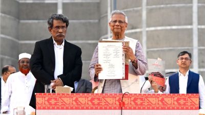 Head of the Bangladesh's interim government and Nobel laureate Dr. Muhammad Yunus, center right, displays a political charter called 'July National Charter' at an event outside Bangladesh's national parliament complex in Dhaka, Bangladesh, Friday, Oct. 17, 2025. (AP Photo/Mahmud Hossain Opu)