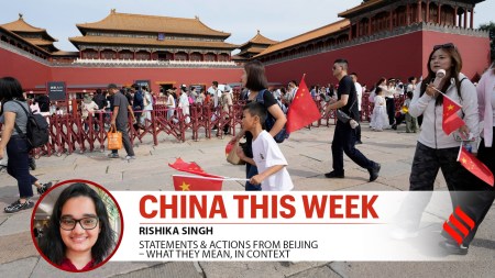 A child runs with Chinese national flags outside the Forbidden City during the National Day holidays in Beijing, China, Wednesday, Oct. 1, 2025.