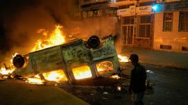 A boy stands next to a torched police vehicle as youth led protests calling for healthcare and education reforms turned violent, in Sale, Morocco, Wednesday, Oct. 1, 2025. (AP Photo/Mosa'ab Elshamy)