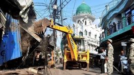 Security personnel stand guard while shops on alleged illegal encroachments being demolished by the authorities, in Bareilly, Uttar Pradesh, Saturday, Oct. 4, 2025. (PTI Photo)
