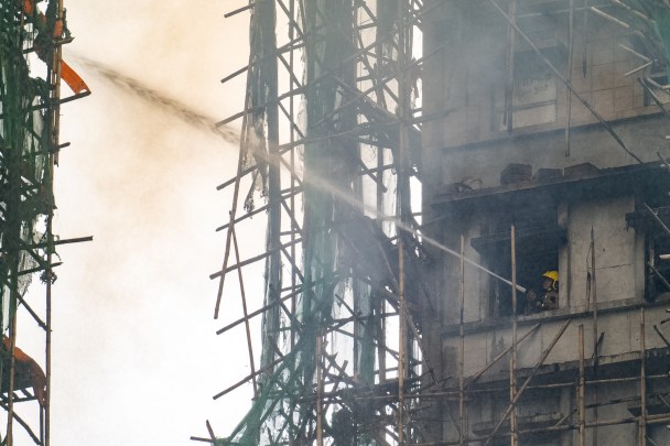 A firefighter works to extinguish a fire that broke out at Wang Fuk Court, a residential estate in the Tai Po district of Hong Kong's New Territories, Thursday, Nov. 27 2025. (AP Photo/Chan Long Hei)
