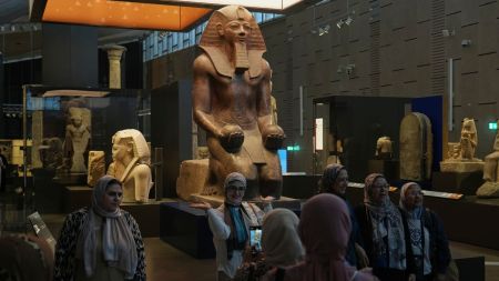 Visitors pose for a group photo under Hatshepsut statue, at the Grand Egyptian Museum in Giza, Egypt, Friday, May 23, 2025. (AP Photo/Amr Nabil)