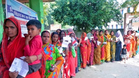 Voters wait in a queue to cast their votes at a polling booth during the second and final phase of the Bihar Assembly elections