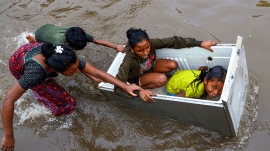 Children play on a waterlogged road following heavy rain triggered by Cyclone Ditwah, in Chennai, Tuesday,
