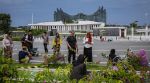 A group relaxes by a pathway lined with flowers and other plantings in front of the Presidential Palace in Nusantara, Indonesia, Nov. 16, 2025. (The New York Times)