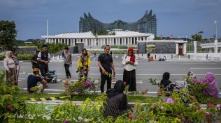 A group relaxes by a pathway lined with flowers and other plantings in front of the Presidential Palace in Nusantara, Indonesia, Nov. 16, 2025. (The New York Times)