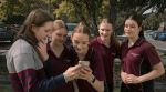 Jasmine Bentley, center, and Amelie Tomlinson, far right, watch a TikTok video with their friends in Melbourne, Australia, Nov. 13, 2025.