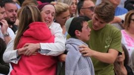 A family reacts during a menorah lighting ceremony at a floral memorial for victims of Sunday's shooting, at the Bondi Pavilion on Bondi Beach on Tuesday, Dec. 16, 2025, in Sydney, Australia. (AP Photo/Mark Baker)