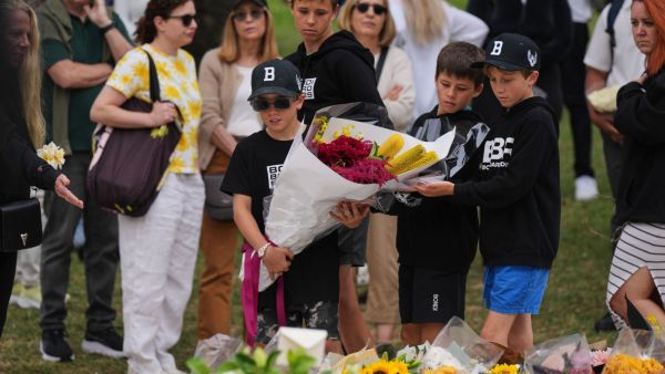 Boys lay flowers at a flower memorial for victims of Sunday's shooting at the Bondi Pavilion at Bondi Beach on Tuesday, Dec. 16, 2025, in Sydney, Australia. (AP Photo/Mark Baker)