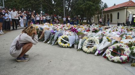 A young woman kneels down by a floral tribute by the Bondi Pavilion at Bondi Beach on Tuesday, Dec. 16, 2025, following Sunday's shooting in Sydney, Australia. (AP Photo/Mark Baker)