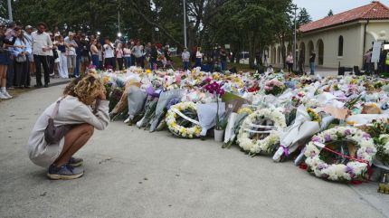 A young woman kneels down by a floral tribute by the Bondi Pavilion at Bondi Beach on Tuesday, Dec. 16, 2025, following Sunday's shooting in Sydney, Australia. (AP Photo/Mark Baker)