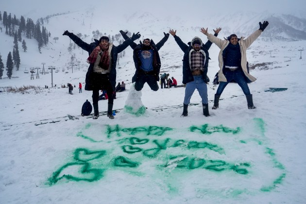 Tourists pose for photographs near a ‘Happy New Year 2026’ message scribbled on snow at Kongdori in Gulmarg. (PTI Photo)