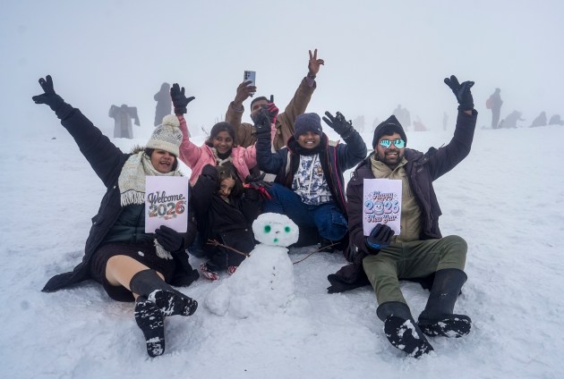 Tourists pose for photographs near a snowman at Kongdori in Gulmarg. (PTI Photo)