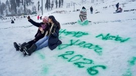 Tourists take a selfie near ‘Happy New Year 2026’ message scribbled on snow with spray paint, at Kongdori, in Gulmarg, Baramullah district, Jammu and Kashmir. (PTI Photo)