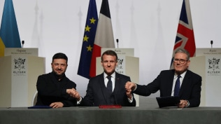 Ukraine's President Volodymyr Zelenskyy (left) France's President Emmanuel Macron and Britain's Prime Minister Keir Starmer shake hands. The flags of the respective countries are seen in the background