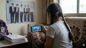 Young girl watching Korean idols dancing on phone screen depicting parasocial bonds